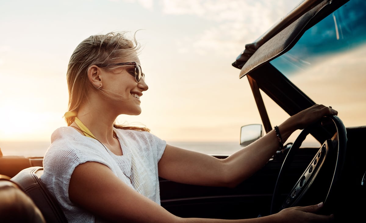Shot of a happy young woman enjoying a summer's road trip